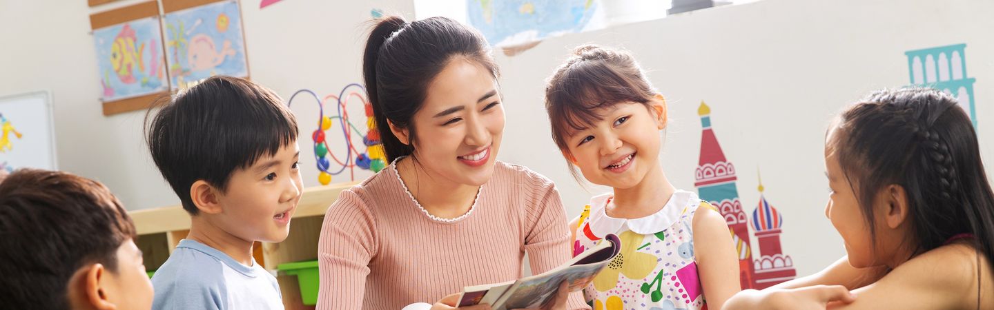 老師和幼兒圍坐在一起看書,孩子們開心地笑