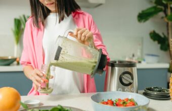 媽媽在明亮廚房把果汁機打好的蔬菜泥倒進杯子