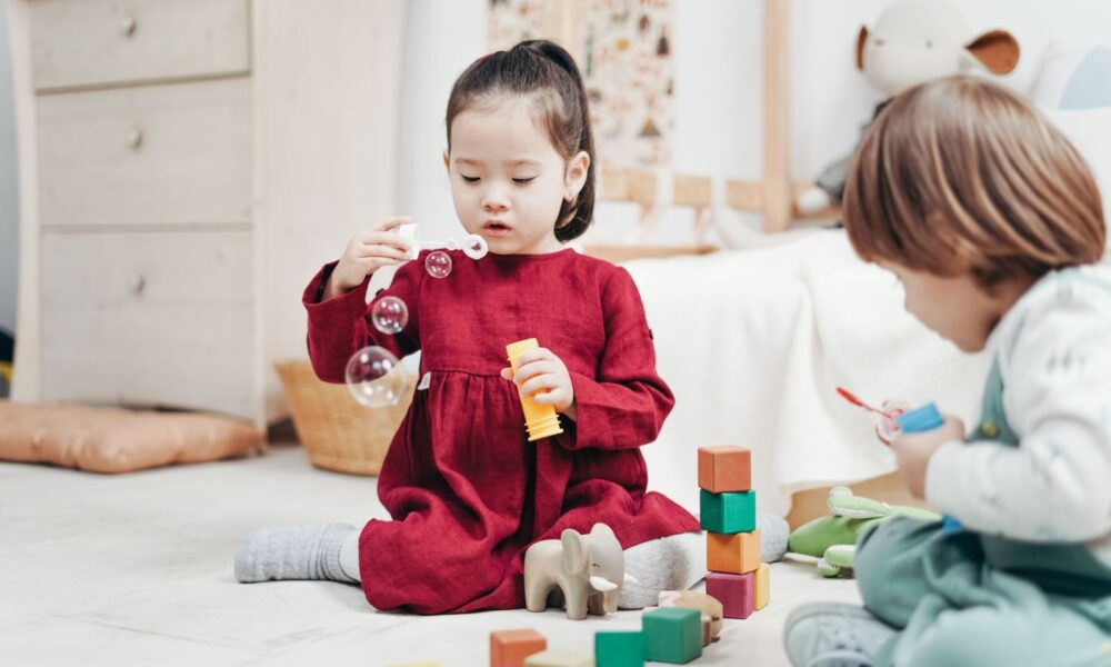 兩個孩子在明亮的居家遊戲角玩積木、吹泡泡