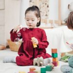 兩個孩子在明亮的居家遊戲角玩積木、吹泡泡