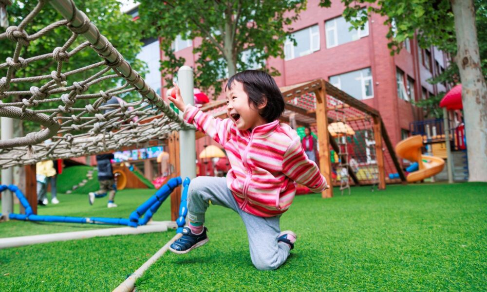 小女孩在幼兒園草地遊戲區開心地跑跳