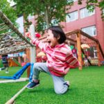 小女孩在幼兒園草地遊戲區開心地跑跳