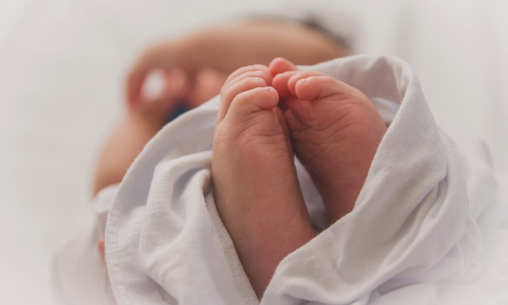 裹在白色包巾裡的新生兒，露出兩隻小腳丫